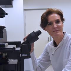 Dr Helen Forgham in front of a microscope in the AIBN labs. 
